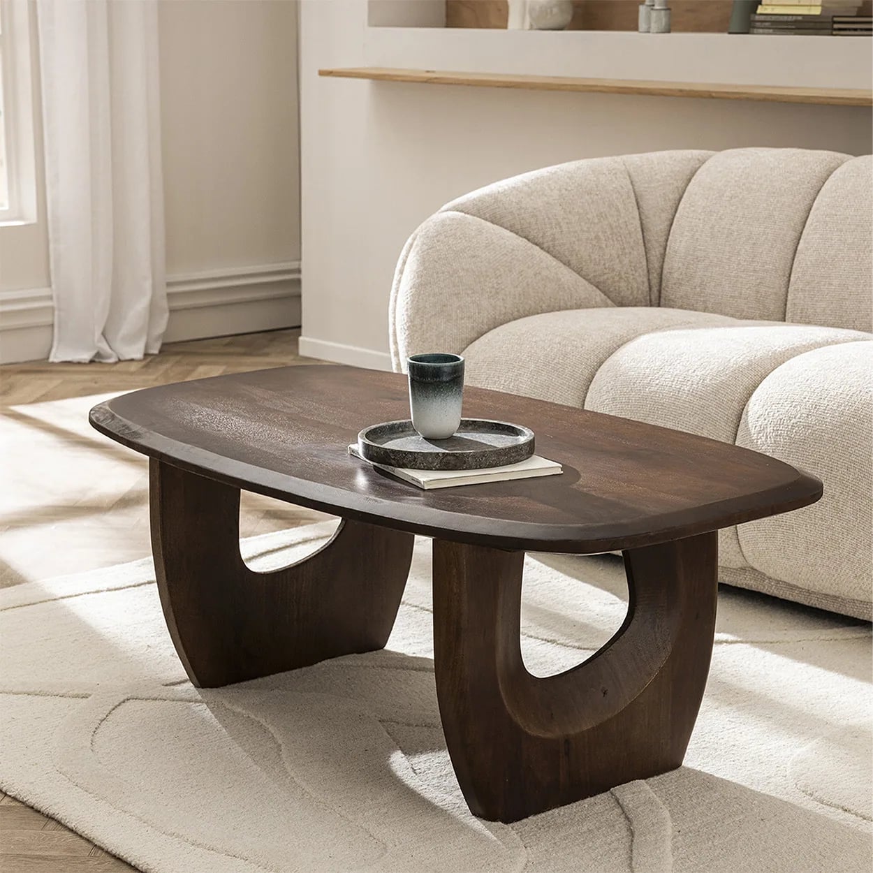 Table basse en bois massif devant un canapé dans un salon contemporain